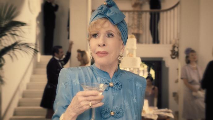 Carol Burnett in a sky blue 60s outfit, including hair turban, looking shocked
