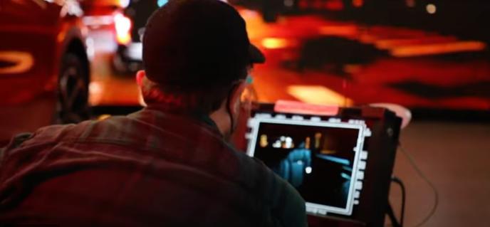 A supervisor watches a monitor on set