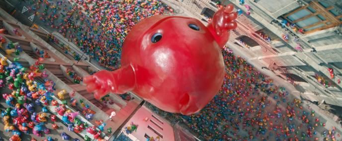A giant red monster made out of candy in a city surrounded by hundreds of nerds characters