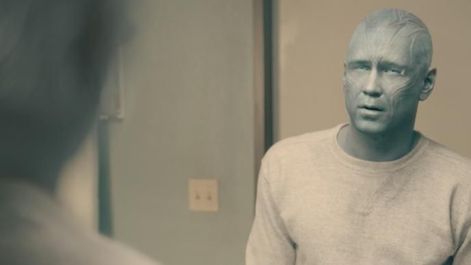 Colin Farrell as John Sugar in alien form looking at his reflection in a mirror.