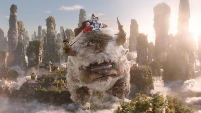 Appa from Avatar soars through the sky with Aang, Katara, and Sokka