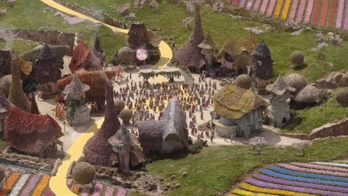 A final shot from Wicked Part One. A distance shot of Munchkinland, with cottages and a digital crowd, CGI tulips, and Glinda's bubble added in visual effects