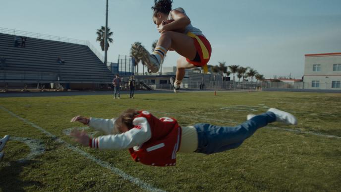 A female flag football player jumps over a male competitor