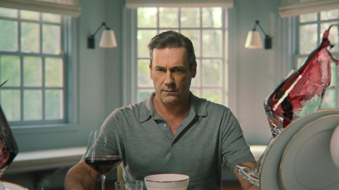 Jon Hamm in Your Friends & Neighbors opening title sequence. He is surrounded by glasses of red wine suspended in air
