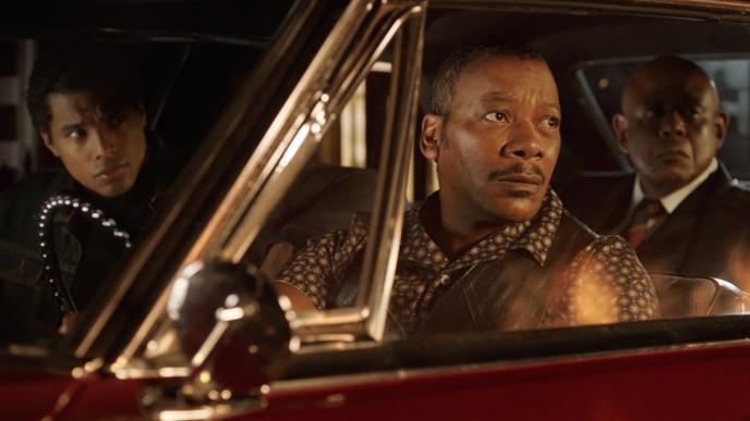 Three characters from Godfather of Harlem season 4 in a car as they look at a fire