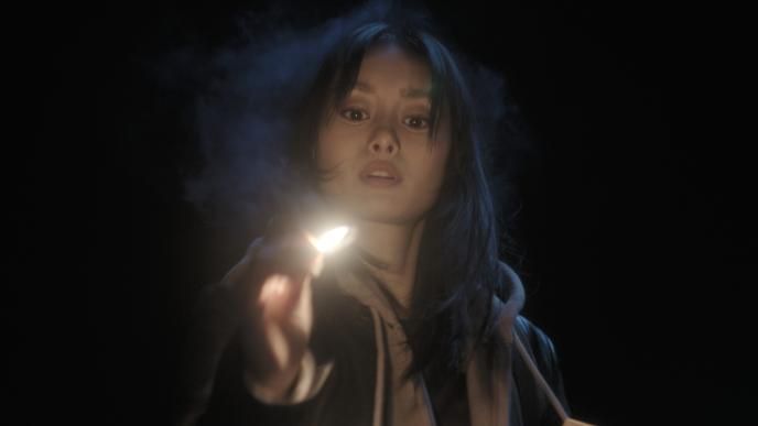 A woman holds a lit match