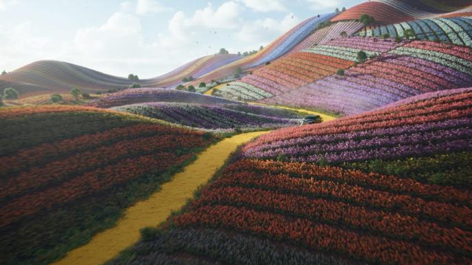 A winding yellow brick road cuts through vibrant, rolling tulip fields from Wicked, with a car driving amid the blooms.