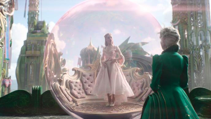 Ariana Grande as Glinda and Michelle Yeoh as Madame Morrible in Wicked: For Good. Glinda stands on her bubble platform with CGI bubble around her and CGI environment behind