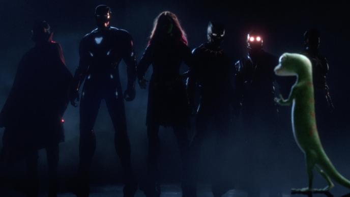 back shot of the geico gecko mascot talking to siz avengers characters