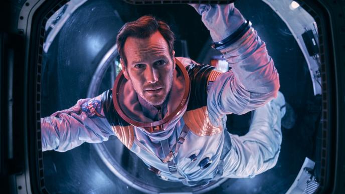 Patrick Wilson floats in a spaceship, looking out of a window