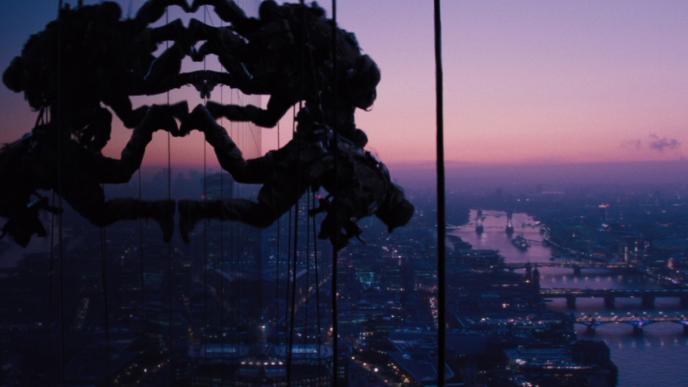 Agents parasail down the side of a glass building at sunset
