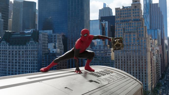 Spider-Man sits on top of a train, holding a cube