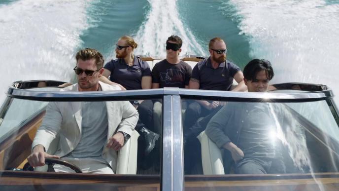 Chris Hemsworth drives a speedboat full of men, one blindfolded.