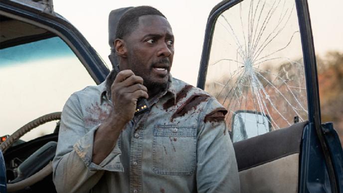 Idris Elba calls for help on a radio from a car with a smashed window