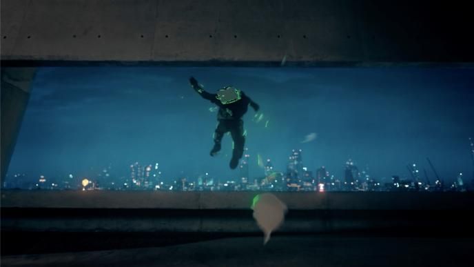 a person jumping out of a building with a city skyline during nighttime in the background