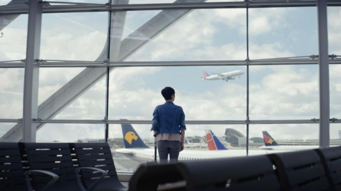 person standing alone at the airport looking at the aeroplanes out the window
