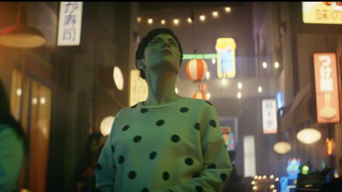 front shot of a person looking up to the sky in front of a chinese street that is lit up by bubble fairy lights and illuminated signs