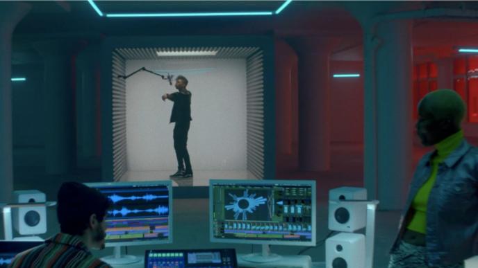 a person singing into a microphone in a recording studio. two people are behind computer screens