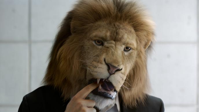businessperson with the head of a lion picking something out of its teeth with its finger