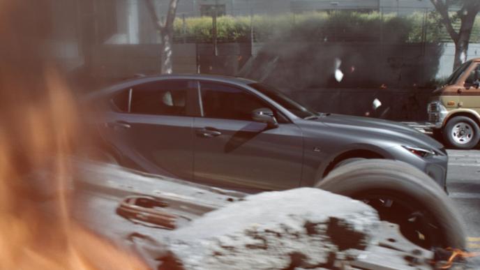 side shot of a lexus car driving by a destroyed cityscape