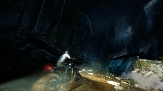 a person riding a motorcycle in the woods during nighttime