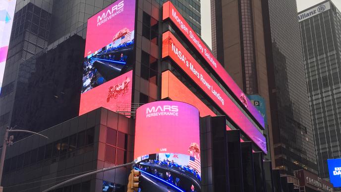 large screens covering cityscapes that are promoting the mars explorer perseverance