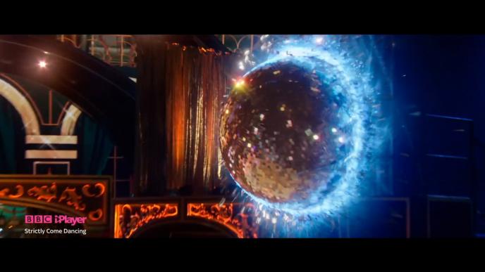 an animated disco ball coming out of a portal on a stage. there is bbc iplayer, stricly come dancing branding on the bottom left