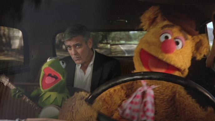actor george clooney in the backseat of a taxi. the taxi is driven by two muppets characters