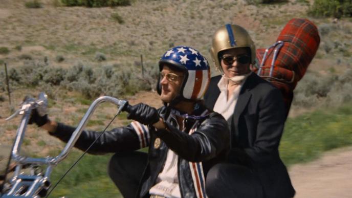 actor george clooney and a person sitting on a harley davison motorcycle