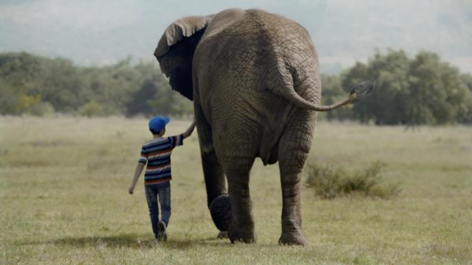 back shot of a child walking alongside an animated elephant