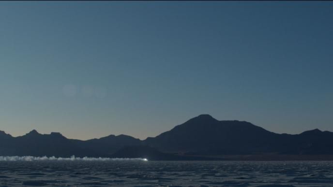 desert mountainous location at dusk with a car driving in the far distance