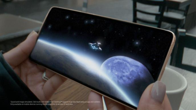 close up shot of a phone screen as someone holds the corners with their fingers. there is a spaceship in space and a planet on the screen