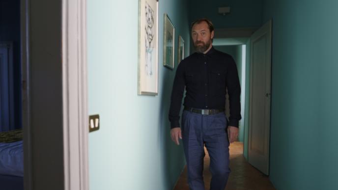 actor jude law standing in front of a cg animated hallway