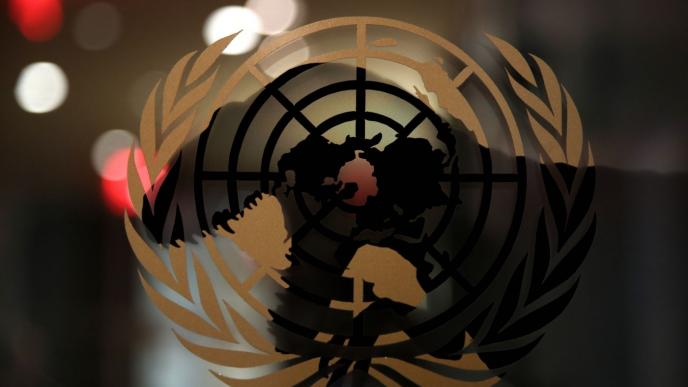 shadow of an animated t-rex dinosasaur in front of a united nations emblem