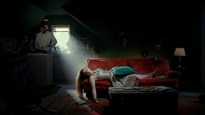 a person sleeping on a sofa in a dress. there is a cushion on their belly