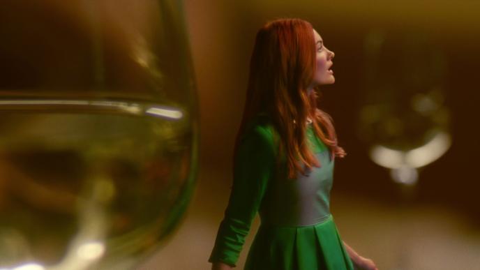 side view of a person looking into the distance in between blurred giant wine glasses