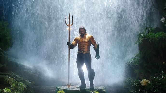 actor jason momoa as aquaman standing in front of a waterfall while holding a trident