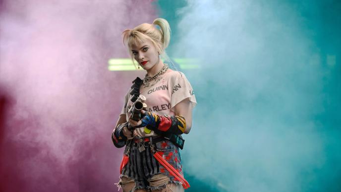 actress margot robbie as harley quinn holding a gun