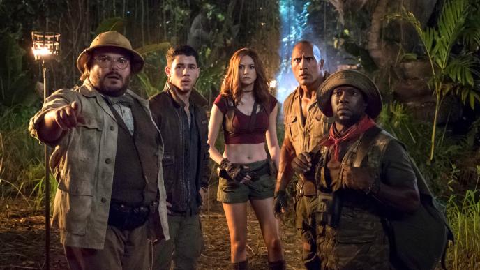five jumanji characters standing together looking ahead to the left in a jungle