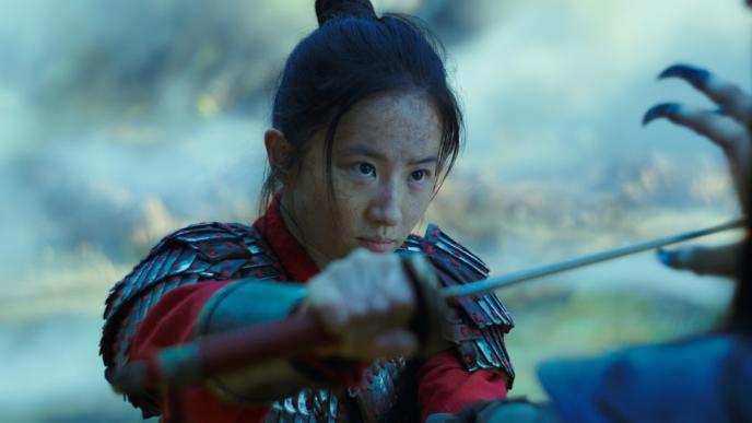 mulan actress liu yifei in warrior armor holding up a sword and looking the enemy directly in the eyes