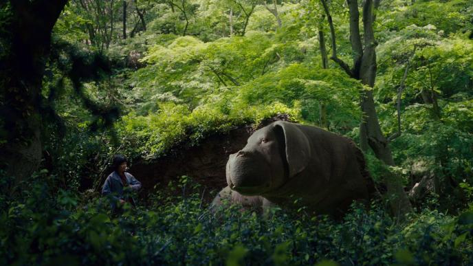 super pig okja looking at actress seo-hyeon ahn as mija standing in a forest