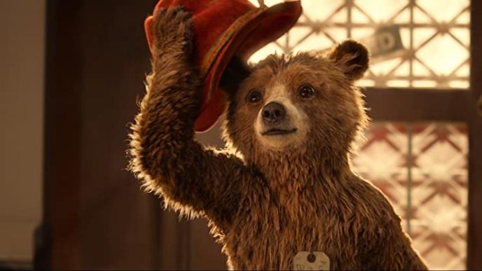 Paddington bear tips his red hat 