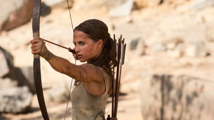 actress alicia vikander as lara croft holding up an archery bow and arrow
