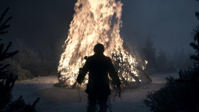 back view of scrooge from a christmas carol standing in front of a large burning bonfire