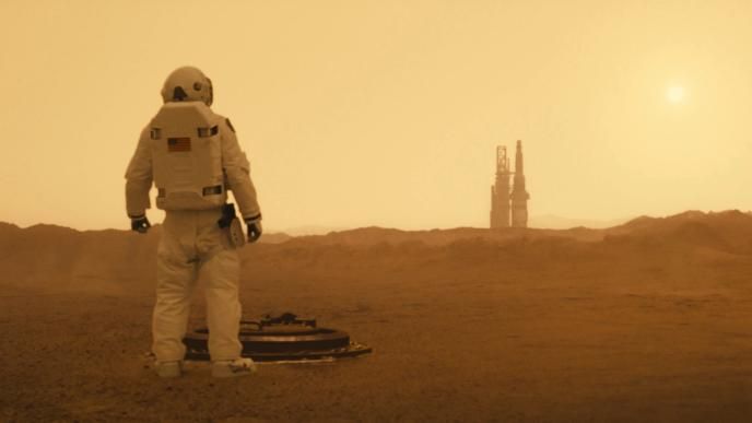 back view of an astronaut looking at a space shuttle station in the distance