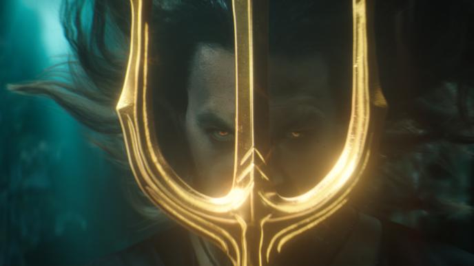 a face close up of actor jason momoa as aquaman staring directly into the camera through the head of a trident