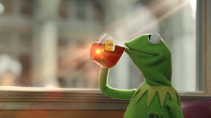 kermit the frog sipping lipton tea out of a clear mug
