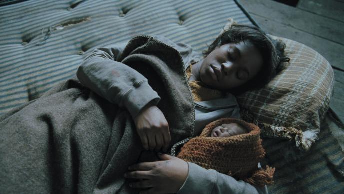 mother and baby from children of men laying down on a mattress
