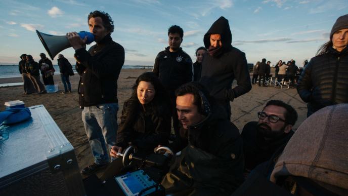 director anh vu sitting on a beach with filmmakers and film crew