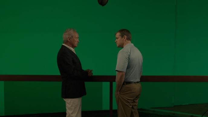 side view of actor christopher waltz as dusan mirkovic and actor matt damn as paul safranek standing in front of a green screen